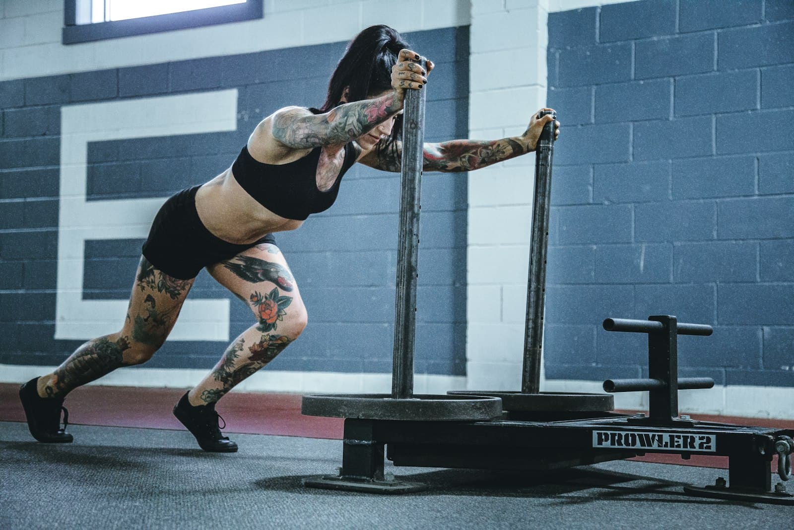 Sporter duwt een sled met gewichten over de vloer van een functional fitness gym