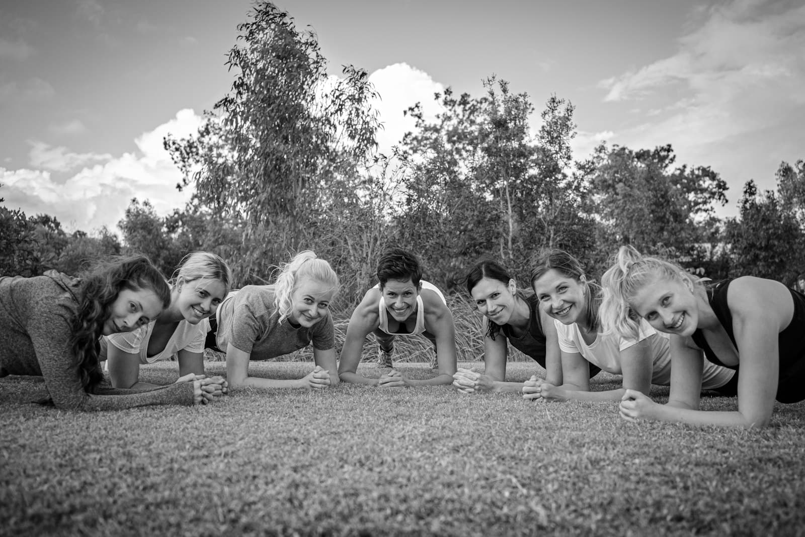 Groep vrouwen houdt samen een plank aan op het gras in het park