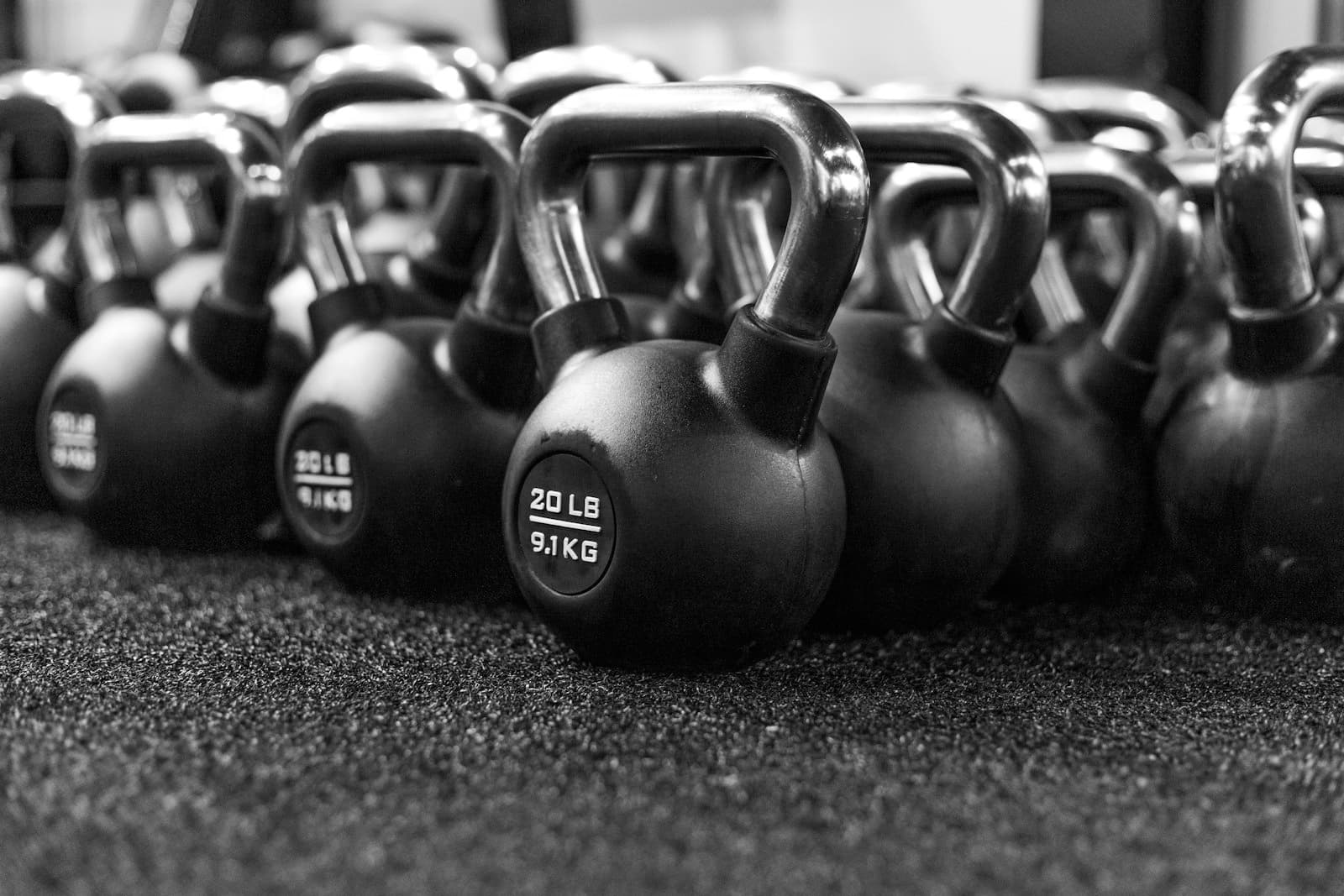 Rij zwarte kettlebells op de rubberen vloer van een trainingsruimte