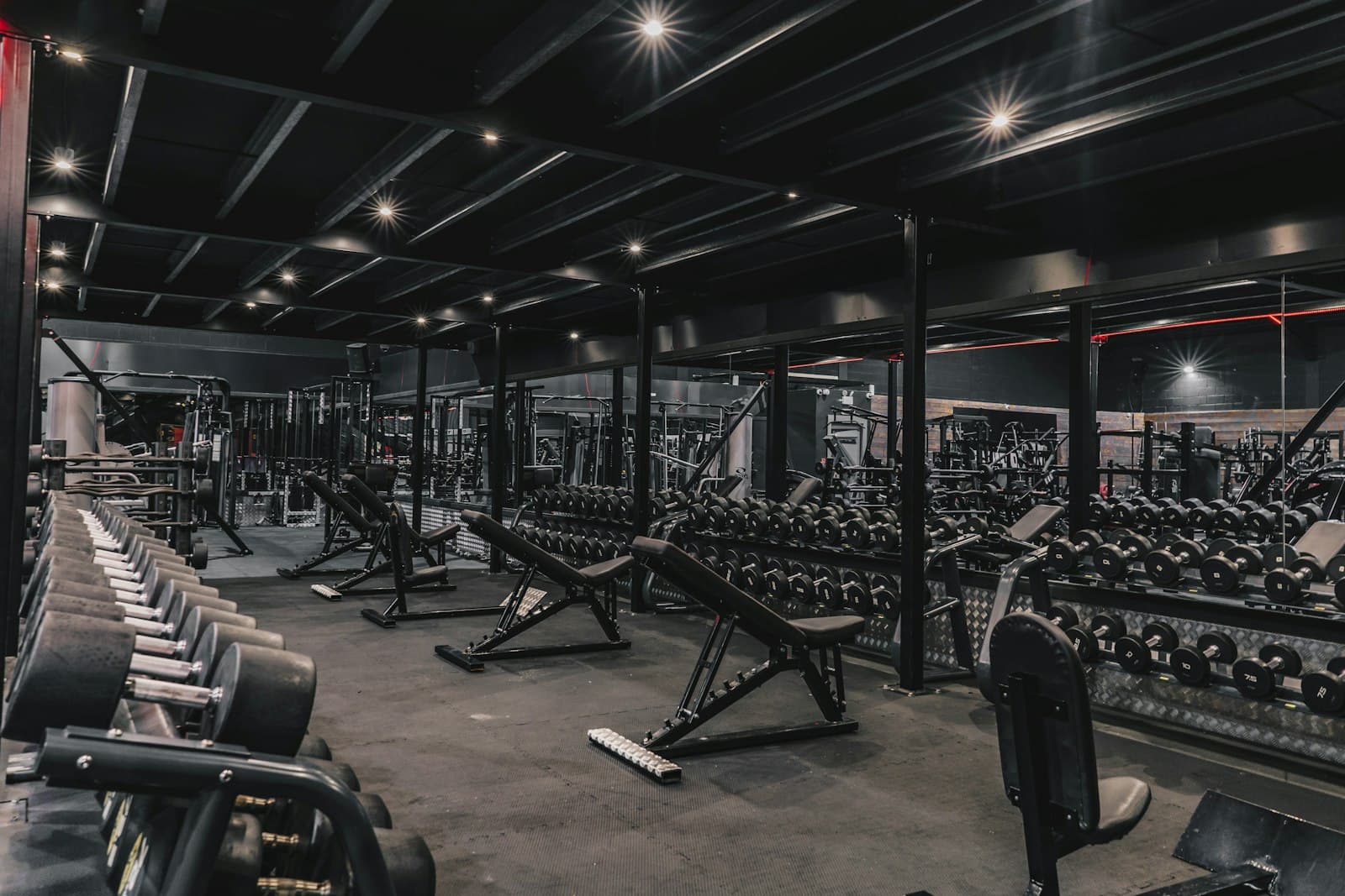 Trainingsvloer van een sportschool met dumbbellrekken, halterbanken en krachtapparaten